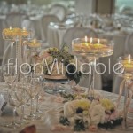 Centrotavola con composizioni floreali e eleganti alzate di vetro con candele 